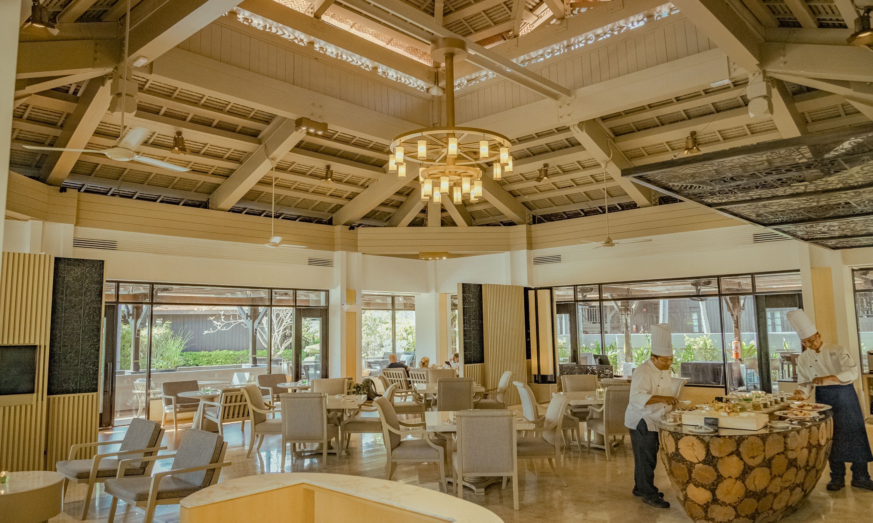 A spacious dining area with high ceilings, large windows, and a central chandelier.