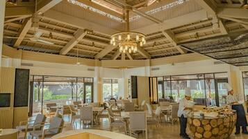 A spacious dining area with high ceilings, large windows, and a central chandelier.