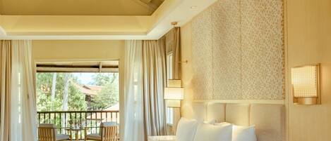 A hotel room with a large bed, a bedside table with a phone, a ceiling fan, and a view of the outdoors.