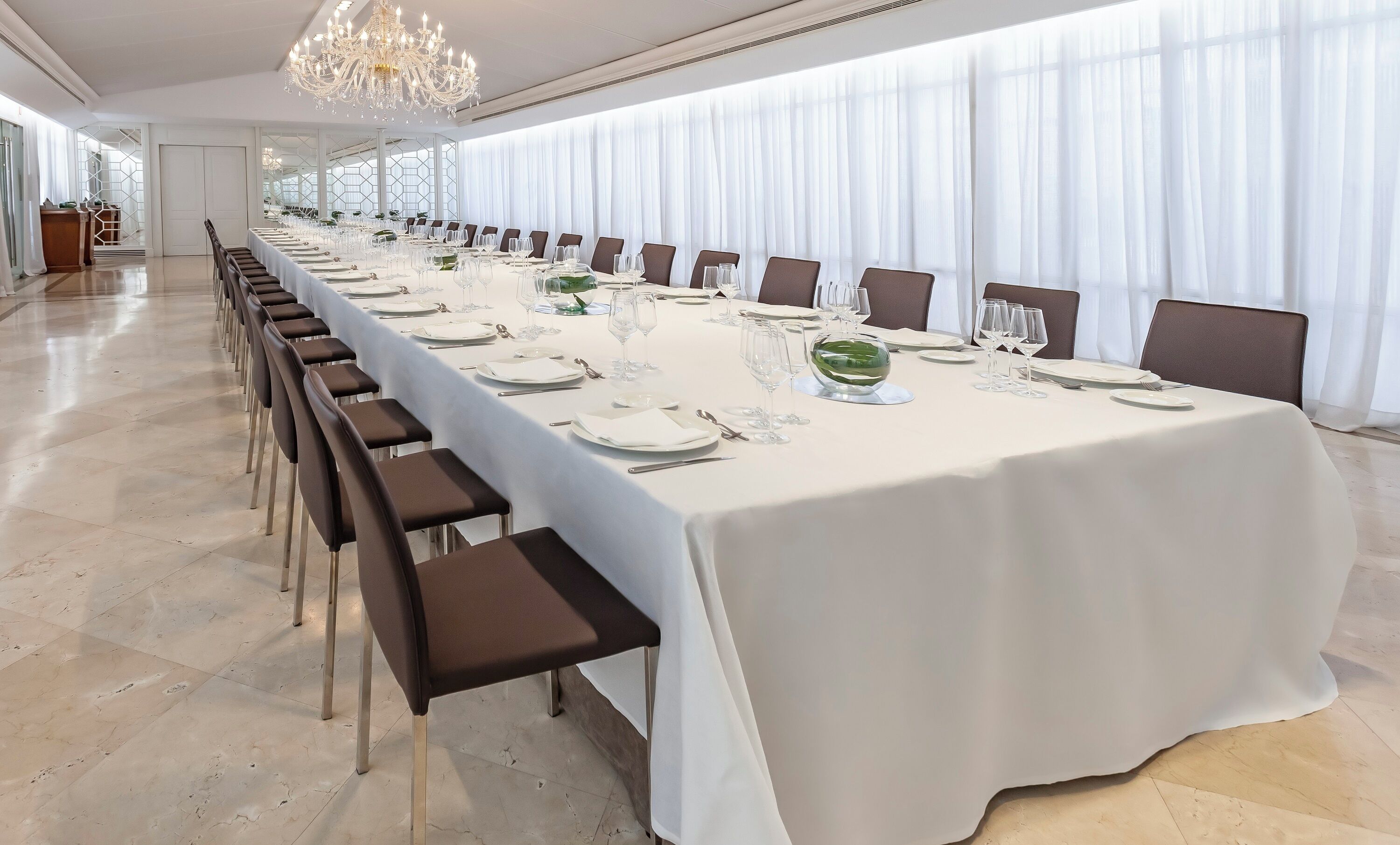 Una larga mesa de banquete dispuesta para un evento formal, con sillas colocadas a ambos lados.