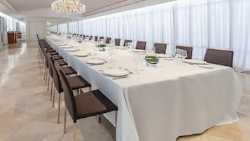 Una larga mesa de banquete dispuesta para un evento formal, con sillas colocadas a ambos lados.
