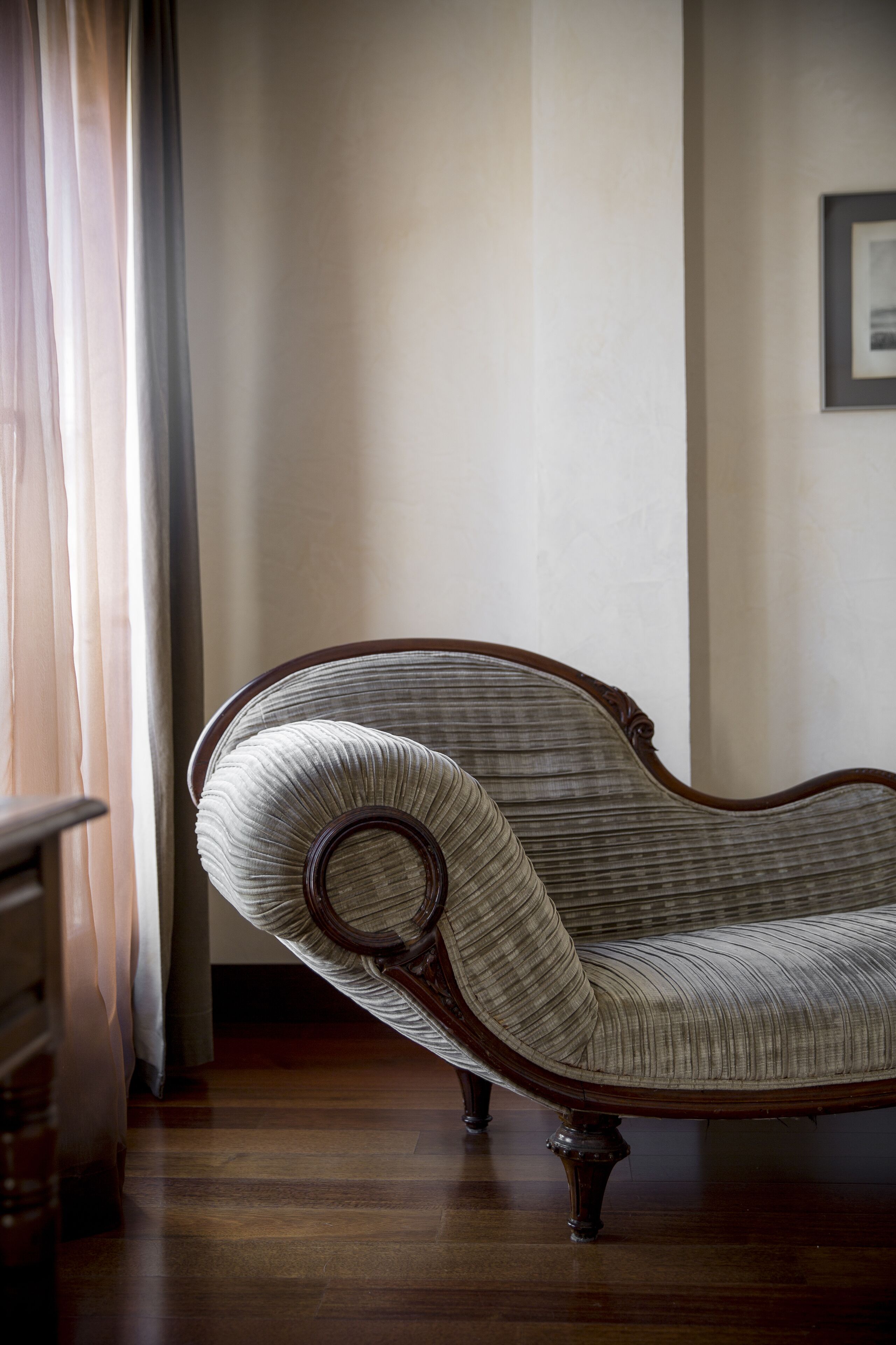 A chair with a curved backrest and wooden legs in a room with a wooden floor and a white wall.
