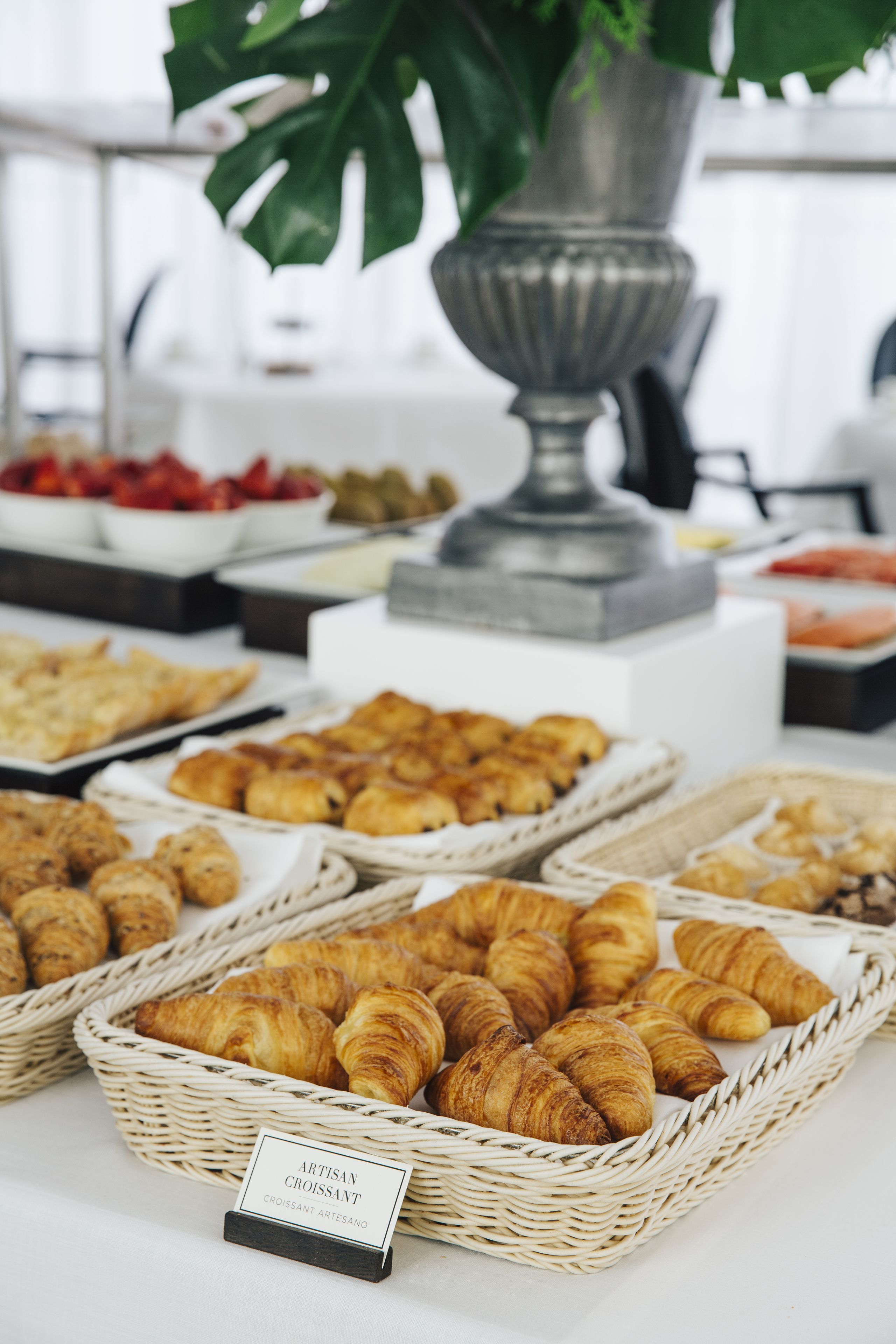 Una mesa de buffet con diversos alimentos, incluyendo croissants y otras vieneserías.