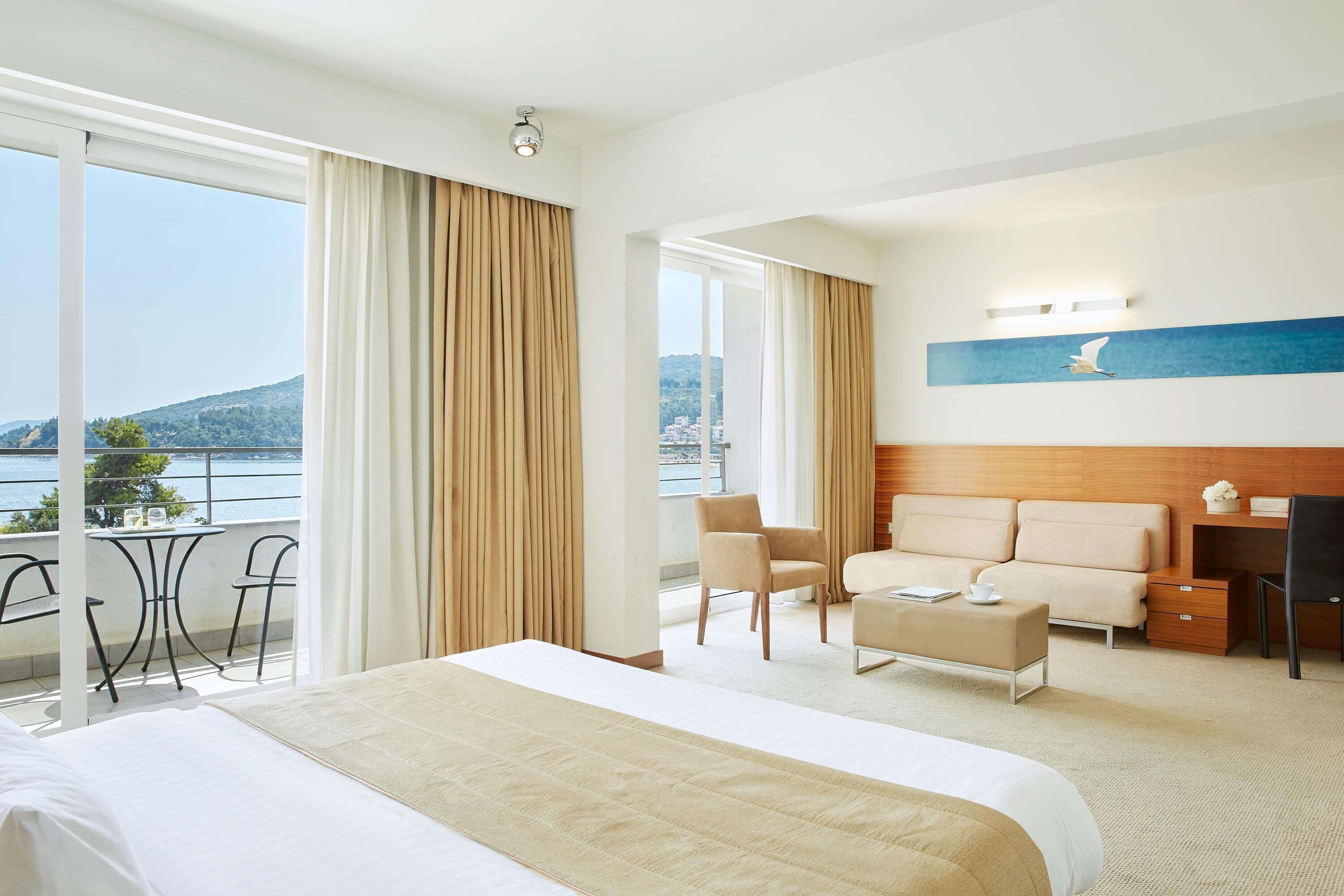 Una habitación de hotel con una cama grande, un escritorio, una silla y vistas al mar.