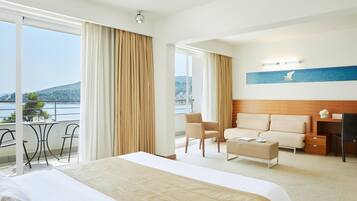 Una habitación de hotel con una cama grande, un escritorio, una silla y vistas al mar.