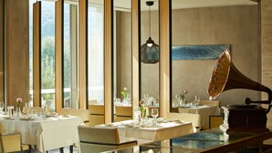 A dining area with tables set for a meal, a gramophone, and large windows allowing natural light.