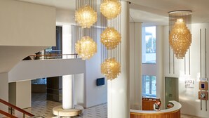 A modern interior with a reception desk, large windows, and decorative chandeliers.
