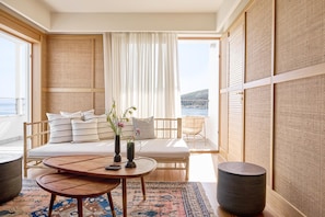 Una habitación con sofá, dos mesas redondas, un ventanal con vistas y decoración tradicional.