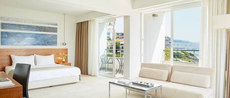 A hotel room with a bed, a sofa, a desk, and a balcony with a city view.
