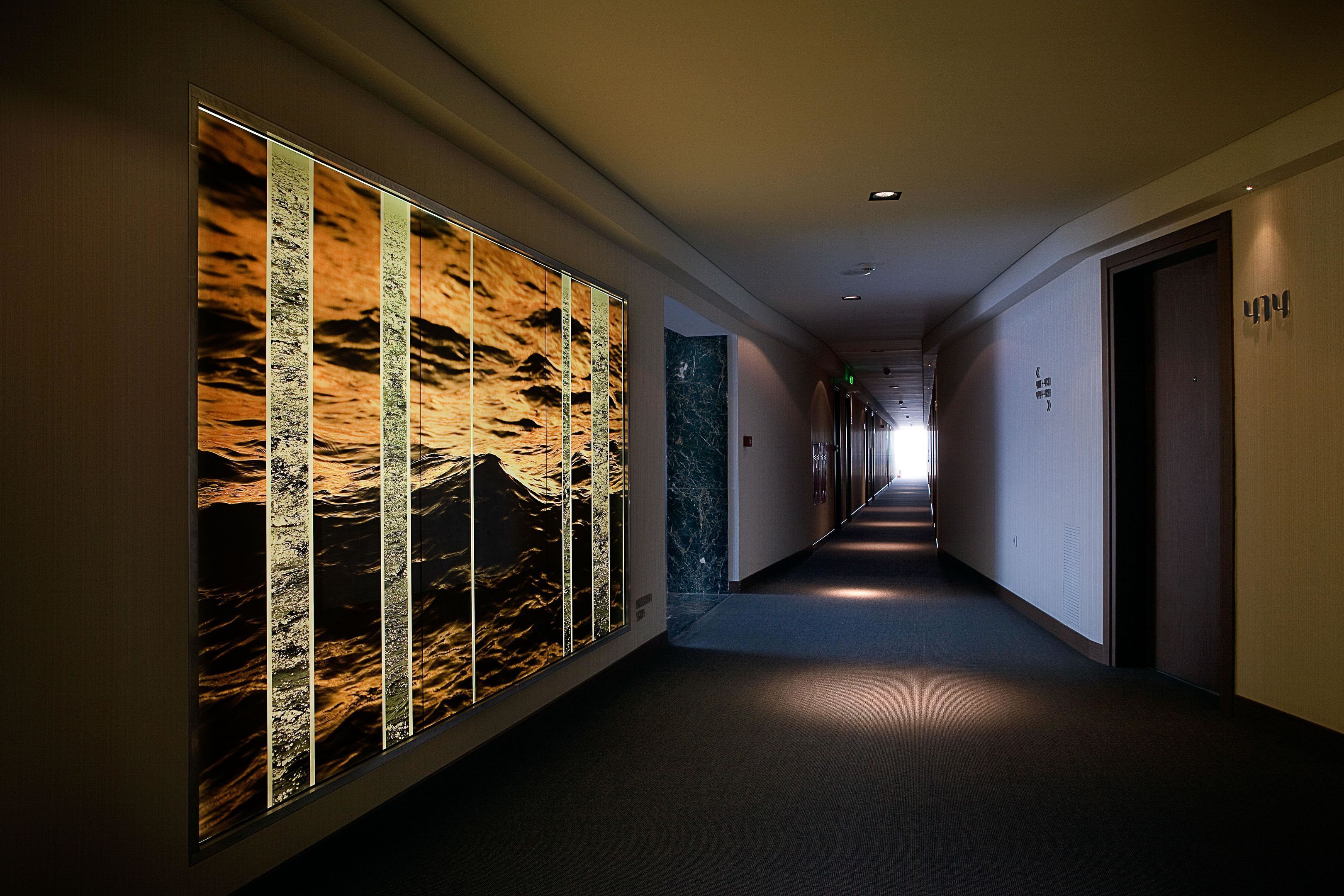 A hallway with a long corridor, a wall with vertical panels, and doors on the right.