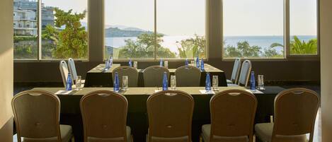 A conference room with a view of the sea and buildings.