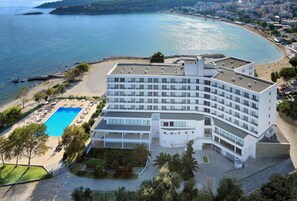 Un hotel moderno con piscina, vistas a la playa y varios balcones.