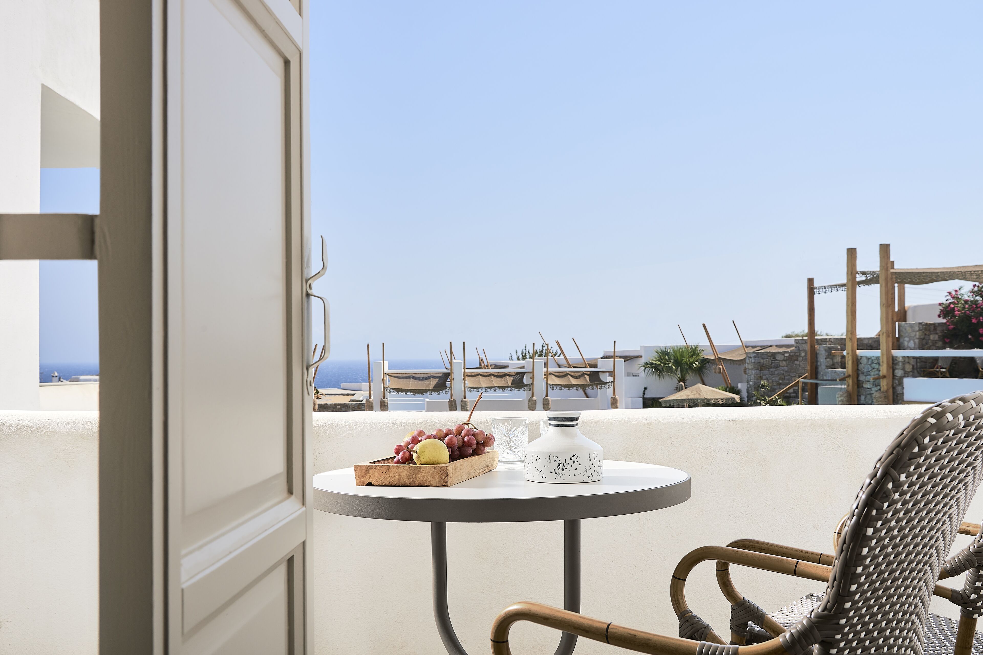 A balcony with a table set with a fruit bowl, a candle, and a decorative item.