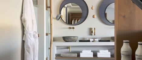 A modern bathroom with a large mirror, a wooden vanity, and a towel rack.