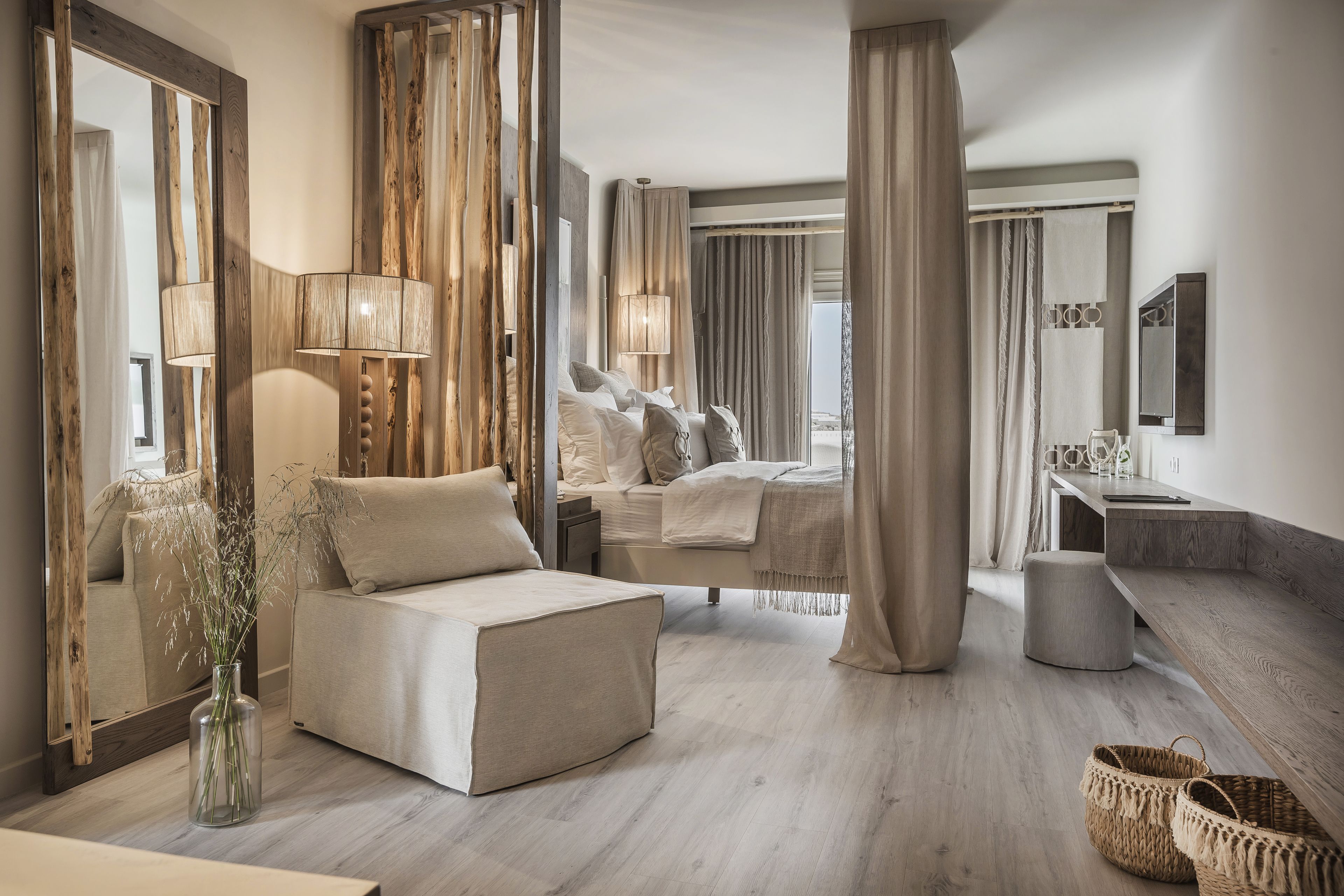 Une chambre d’hôtel moderne dotée d’un grand lit, d’un coin salon, d’une coiffeuse et d’un grand miroir.