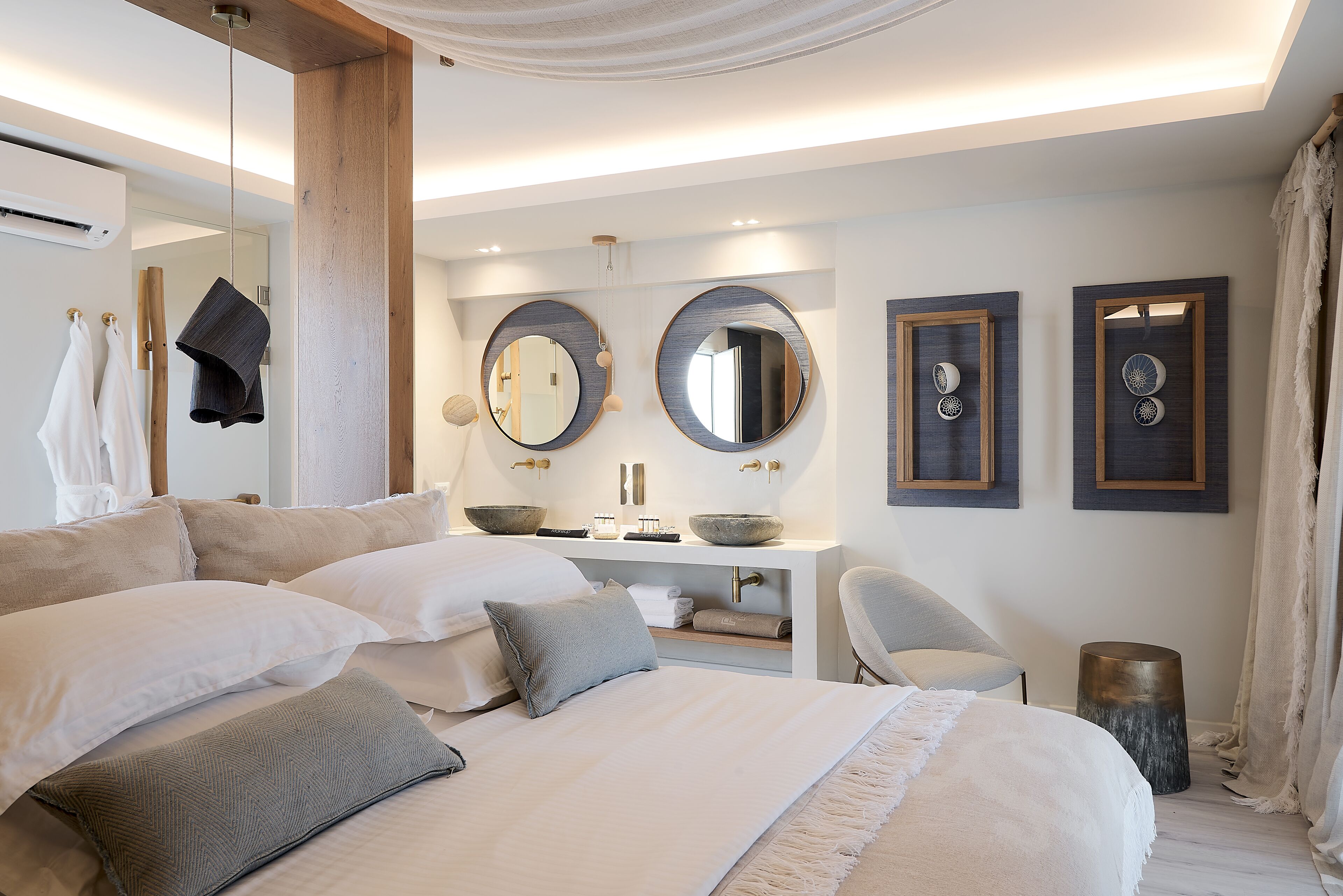A modern bedroom with a large bed, bedside tables, a vanity, and a chair.