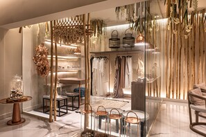 A modern boutique hotel interior with a glass partition, wooden decor, and a clothing rack.