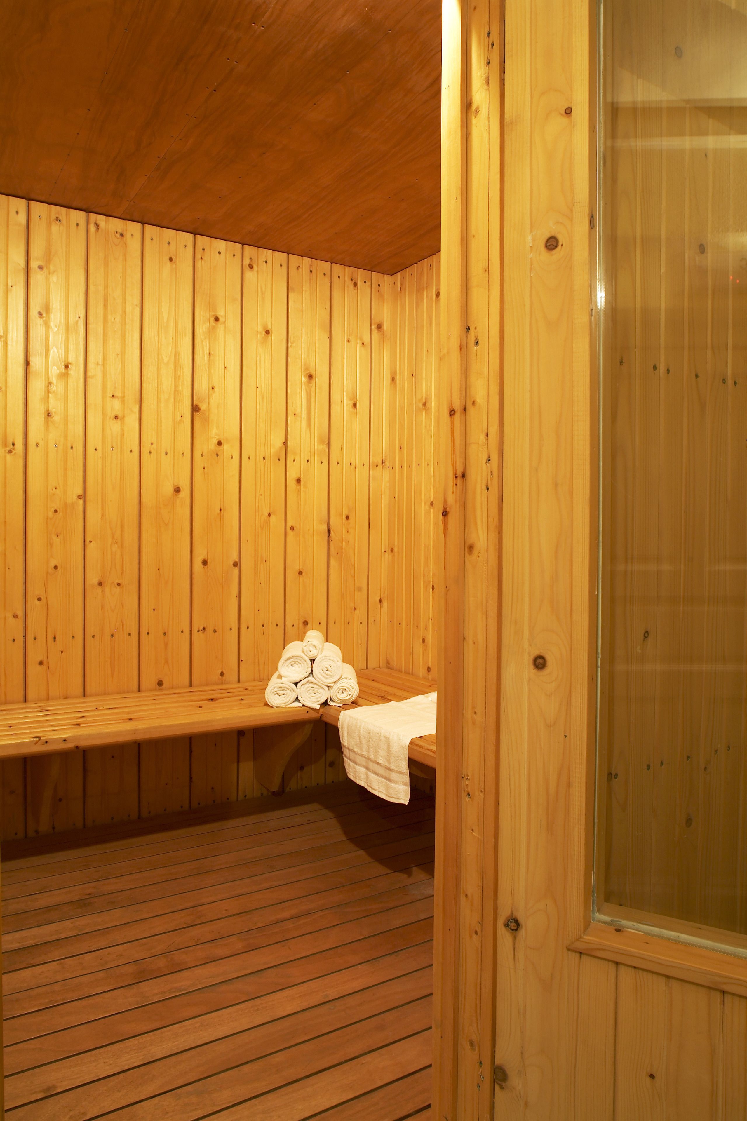 A wooden sauna room with benches and a glass door.