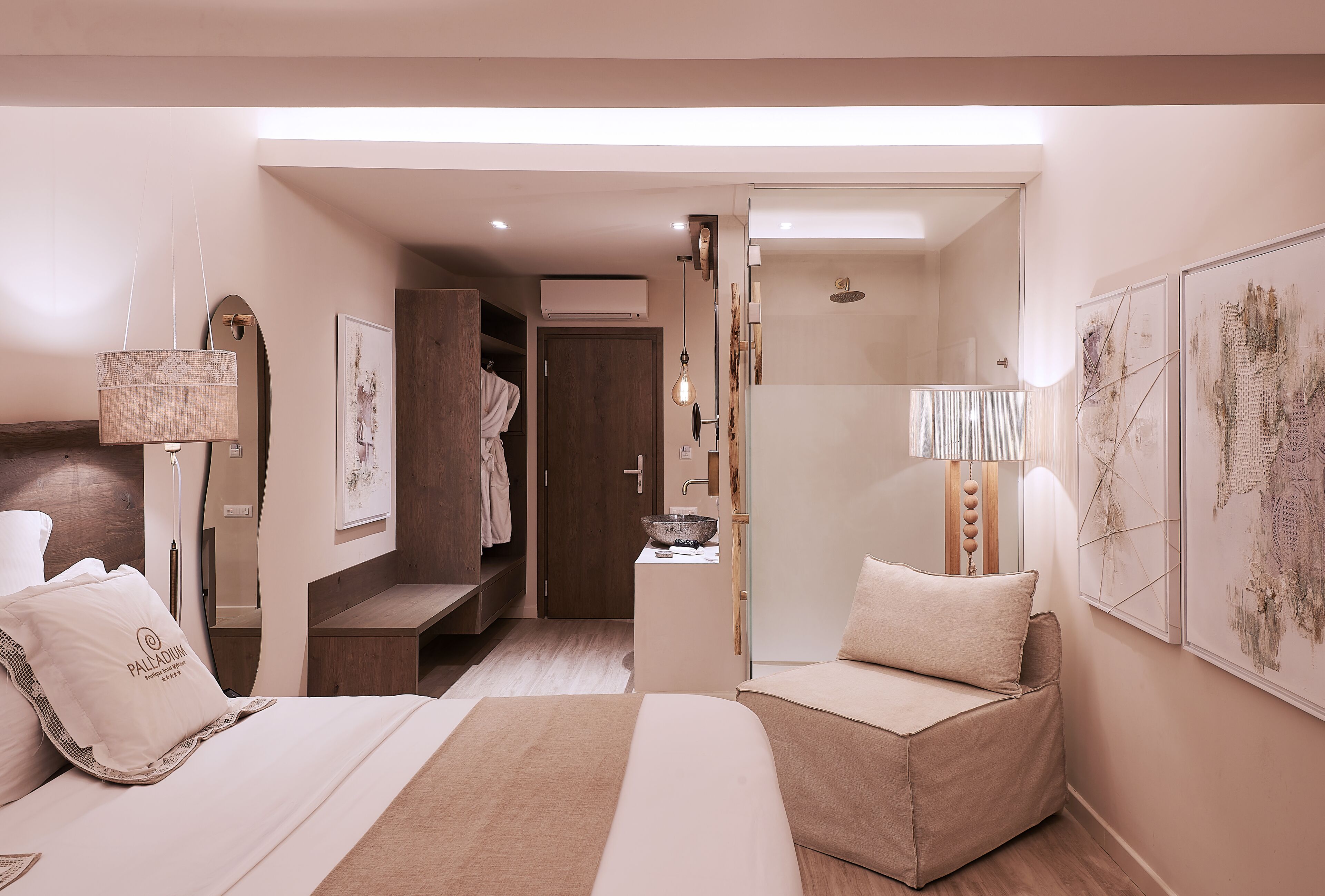Une chambre d’hôtel moderne dotée d’un grand lit, d’un coin salon, d’une coiffeuse avec un miroir et d’œuvres d’art accrochées aux murs.