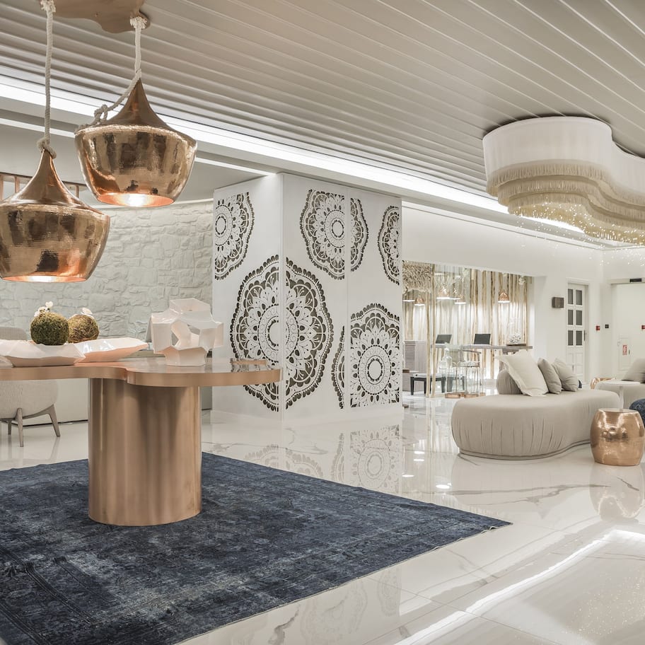 A modern interior with a marble floor, a central table, and a seating area with sofas and ottomans.