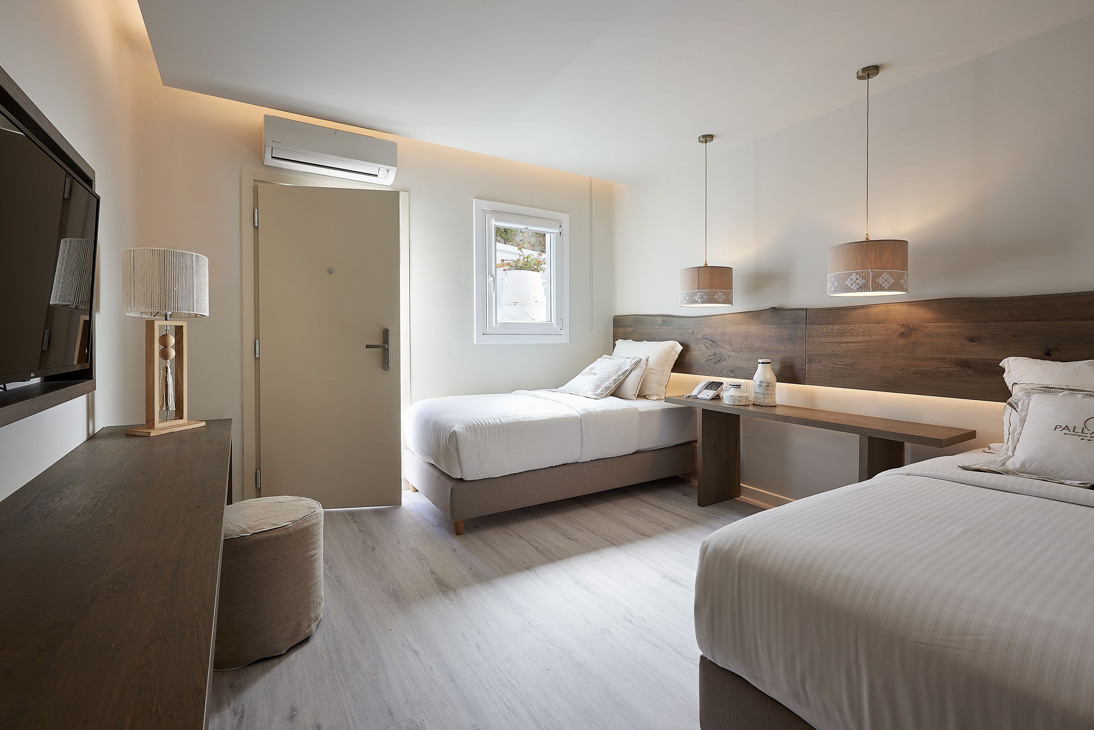 Una habitación de hotel moderna con cama, mesita de noche, lámpara y televisión.