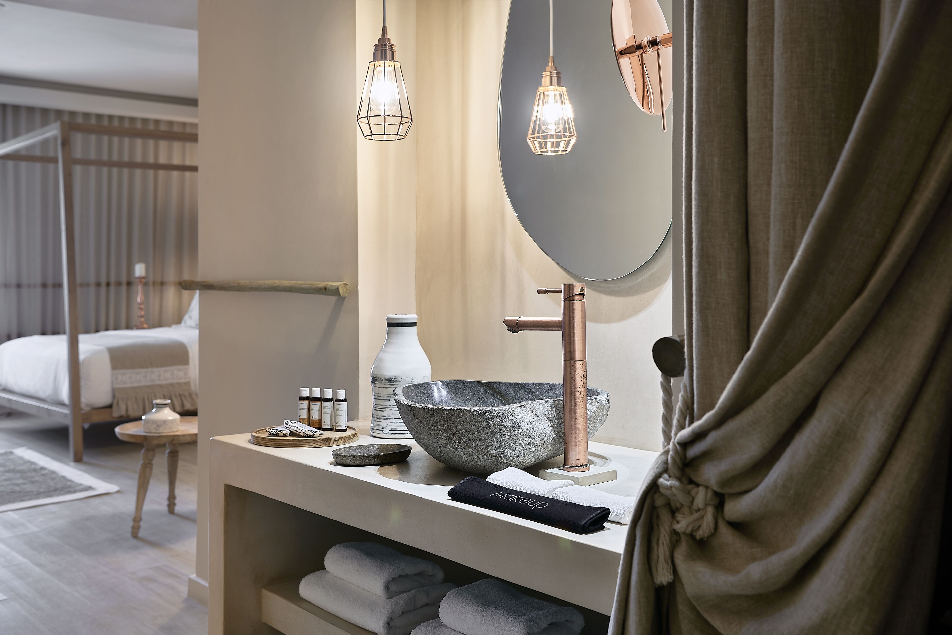 A modern bathroom with a large mirror, stone basin, and two pendant lights.