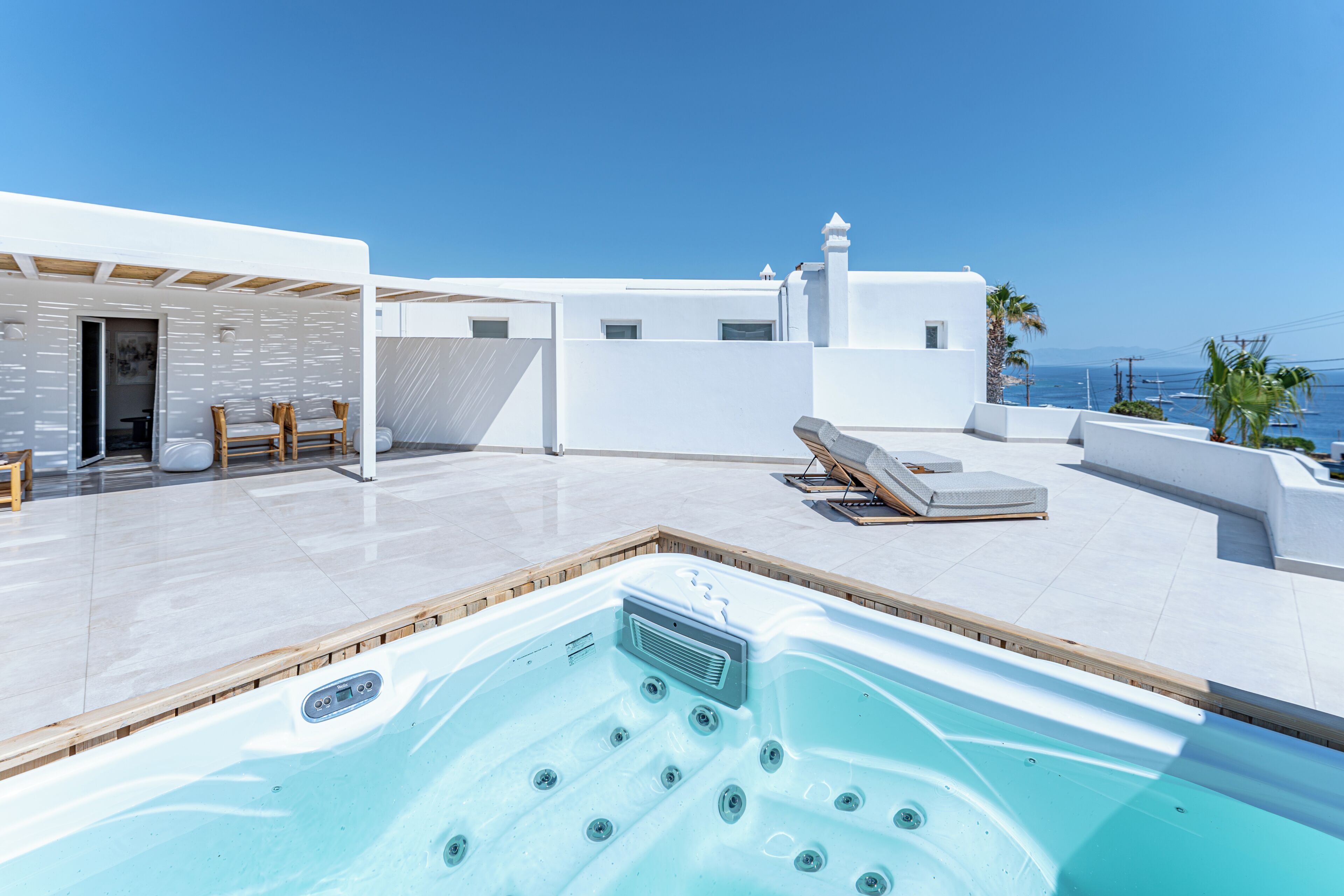 Zona de piscina en la azotea con jacuzzi, sillones de descanso y vistas al mar.