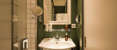 A bathroom with a white sink, a mirror, and a towel hanging on the wall.