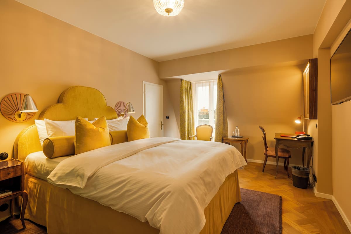 Hotellihuone, jossa on suuri sänky, työpöytä, tuoli ja pieni pöytä.