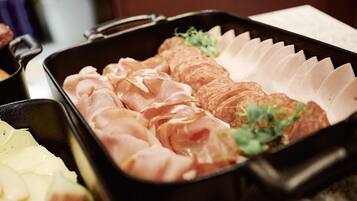 A tray with sliced meats and a small bowl of sauce.