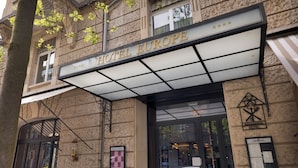 Hotellin sisäänkäynti, jonka yläpuolella on valotaulu, jossa lukee ”HOTEL EUROPE”, ja sen alapuolella toinen valotaulu, jossa lukee ”ROMANTIK HOTEL”.