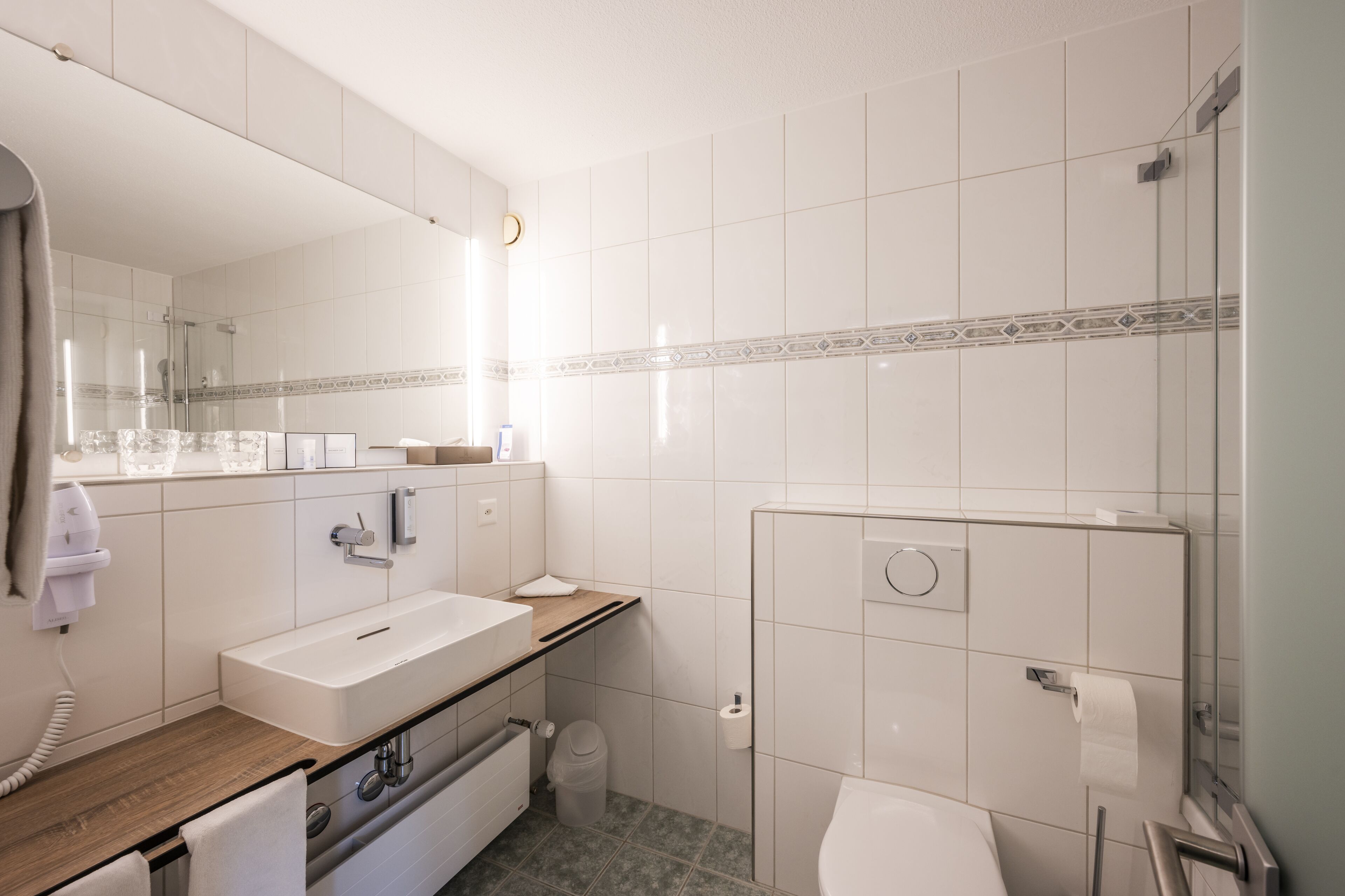 Un baño moderno con lavamanos, espejo y retrete.