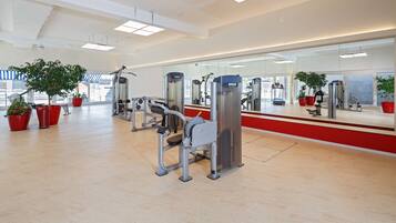 A modern gym with exercise equipment, large windows, and potted plants.