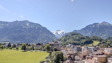 A town with a large open field, buildings, and mountains in the background.