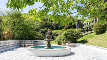 A circular fountain with multiple tiers, surrounded by a white tiled patio with benches.