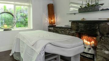 Relax in a serene space with a therapy table, stone fireplace, and peaceful views.