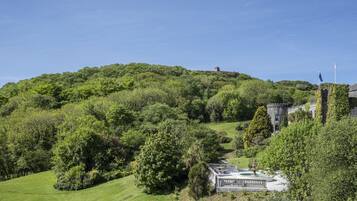 A castle with a tower, surrounded by lush greenery and a clear sky.