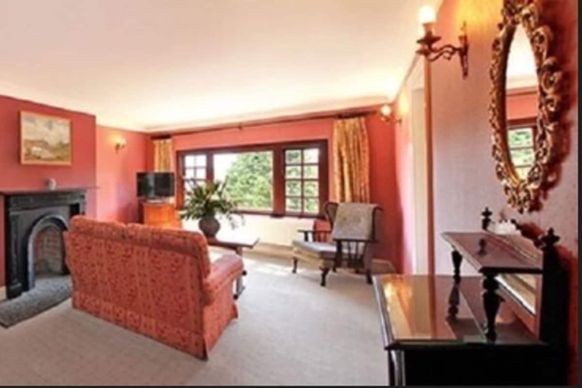 Un salon chaleureux avec une cheminée, un canapé, une table à manger avec des chaises et un grand miroir.