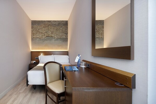 Ein Hotelzimmer mit Bett, Nachttisch, Stuhl und einem großen Spiegel.