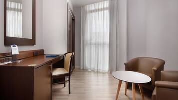 Una habitación de hotel con un escritorio de madera, una silla, una mesa redonda y un espejo grande.