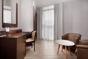 Ein Hotelzimmer mit einem Holztisch, einem Stuhl, einem runden Tisch und einem großen Spiegel.