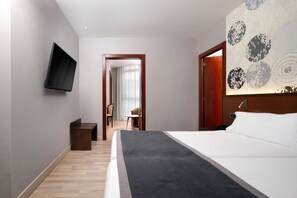 Ein Hotelzimmer mit Bett, Wandfernseher, Schreibtisch und Stuhl.