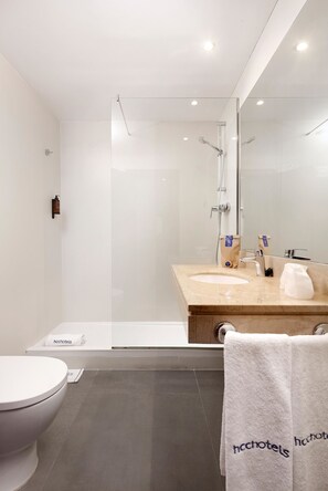 Ein modernes Badezimmer mit einer Duschkabine, einem Waschbecken mit Spiegel und einer Toilette.