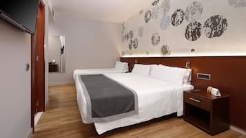 A modern hotel room with a large bed, a bedside table, a flat-screen TV, and a wall with a circular pattern.