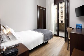 A hotel room with a bed, a desk, a chair, a phone, and a TV. - Hotel HCC Taber (Barcelona)