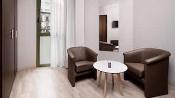 Una habitación moderna con dos sillones de cuero marrón, una mesita redonda, un espejo en la pared y vistas de edificios a través de una puerta.