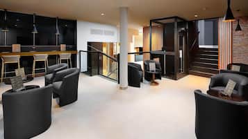 Un interior moderno con una escalera, muebles negros y una zona de bar.