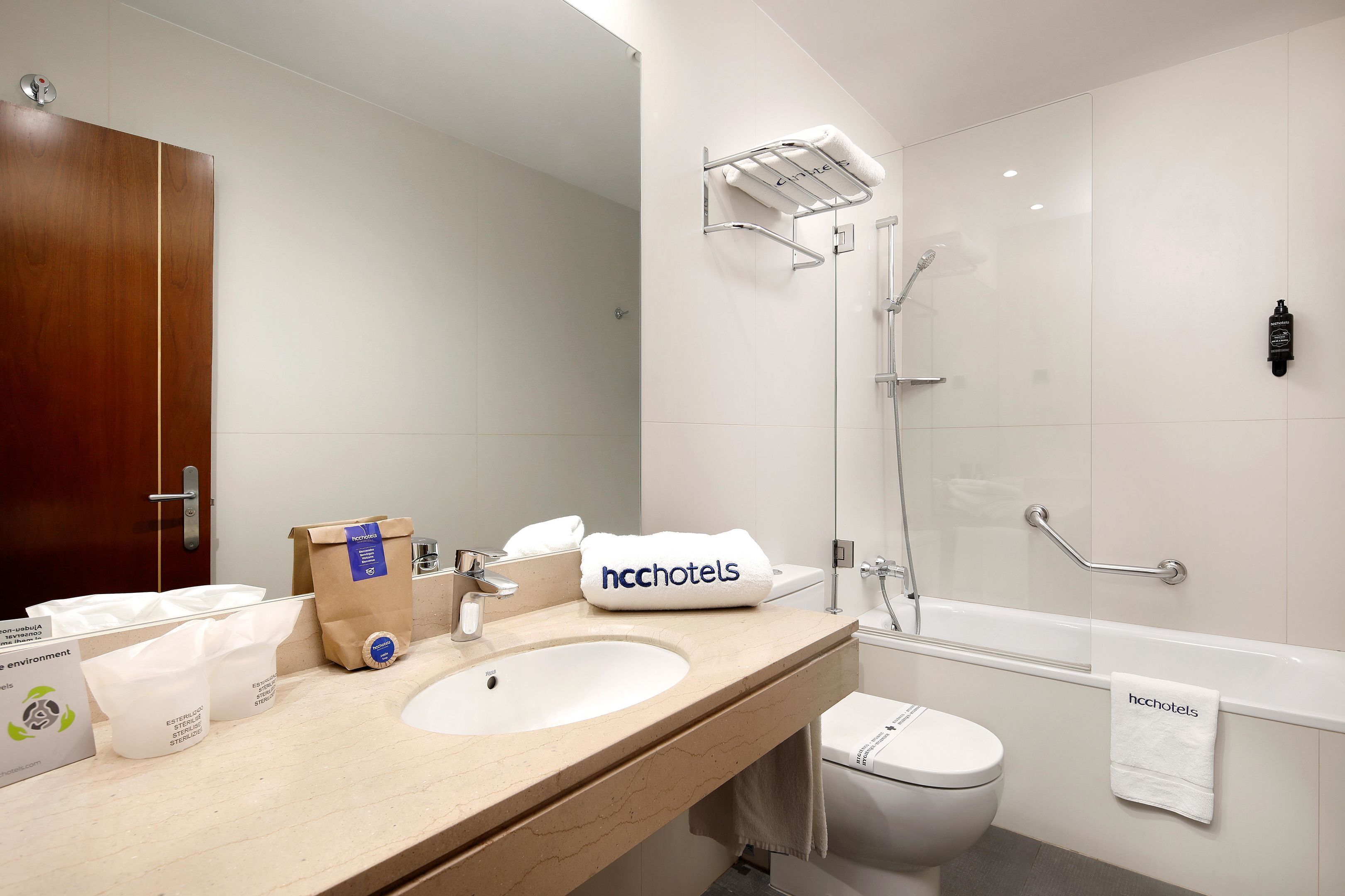 Un baño moderno con tocador de madera, un lavamanos, un espejo, un perchero para toallas, una ducha y un inodoro.