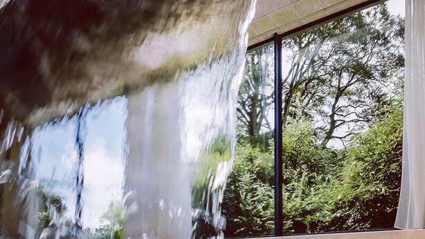 A pool with a waterfall feature and a view of trees through large windows. - Abbey Hotel Roscommon (Roscommon)
