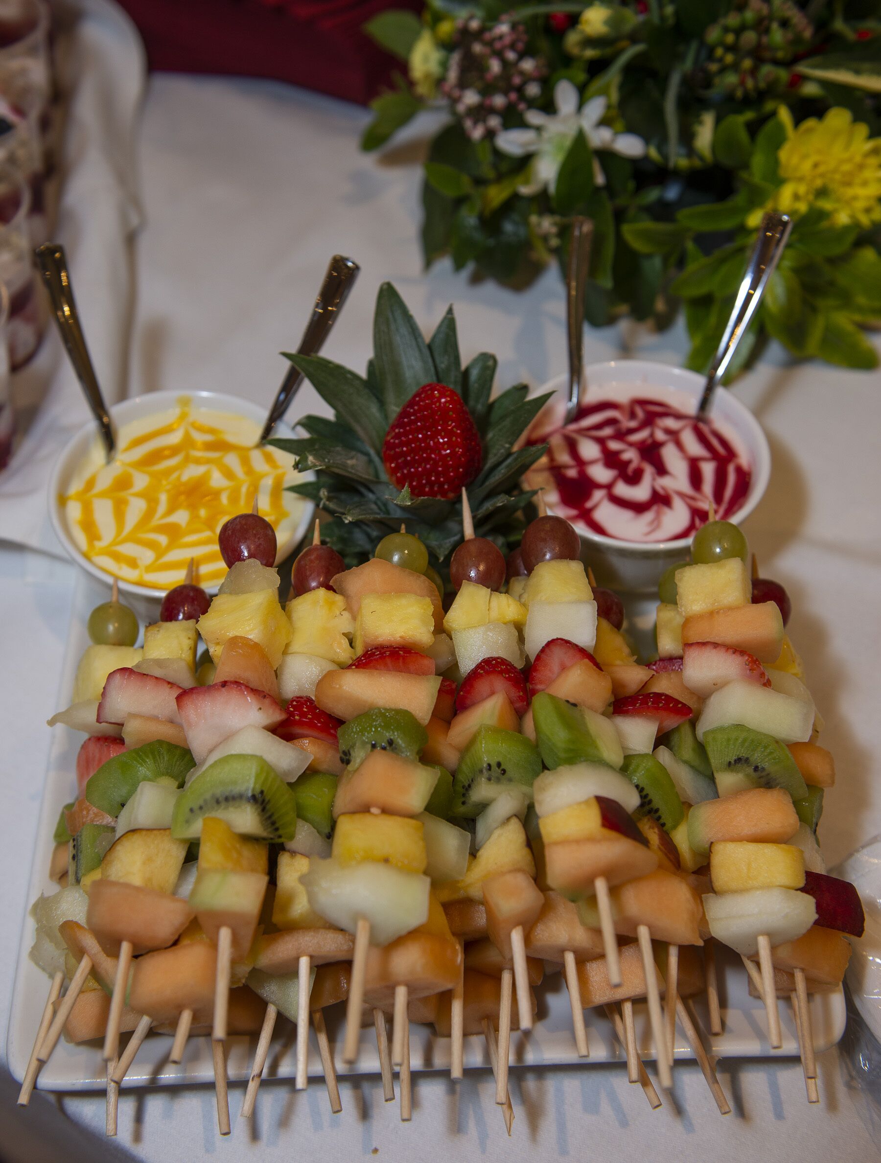 A fruit platter with skewers and two bowls of dessert.